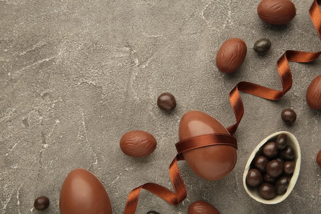 Osterkomposition mit Schokoladeneiern und braunem Band auf grauem Hintergrund Draufsicht