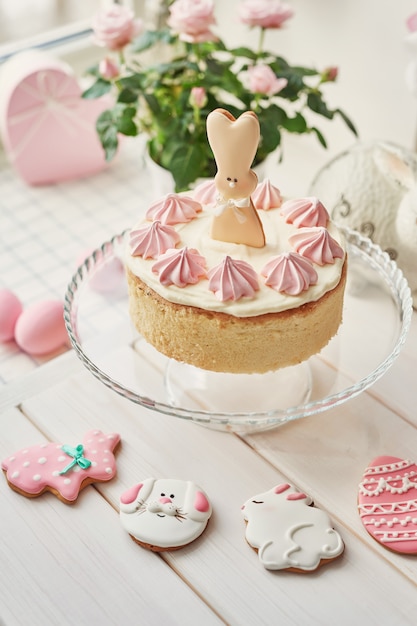 Osterkomposition mit süßem kuchen mit erdbeerglasur, rosa eiern und rosen