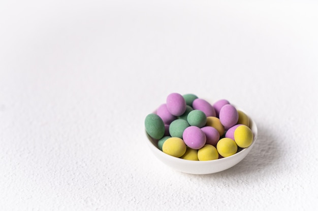 Osterkonzept. Mini-Eier in der kleinen Platte auf weißem Hintergrund. Farbeiermuster, Osternhintergrund.