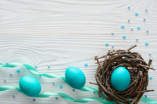 Osterkonzept mit blauen Eiern im Nest auf Holztisch.