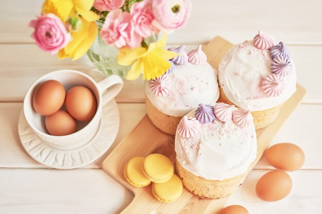 Osterkuchen auf Tisch, Makronen, Eiern und Blumenstrauß in Vaseaster