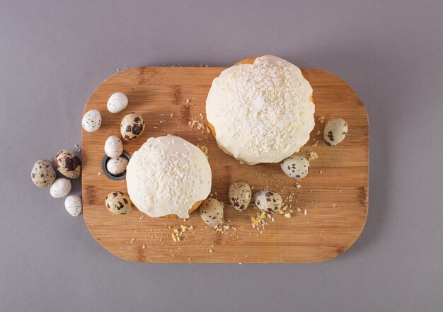 Osterkuchen bedeckt mit Wachteleiern mit weißer Glasur auf einer Draufsicht aus Holzschneidebrett. Thema Ostern