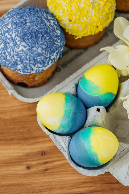 Foto osterkuchen in den farben der flagge der ukraine gelb und blau in einem pappständer mit eiern ostereier platzieren für selektiven textfokus