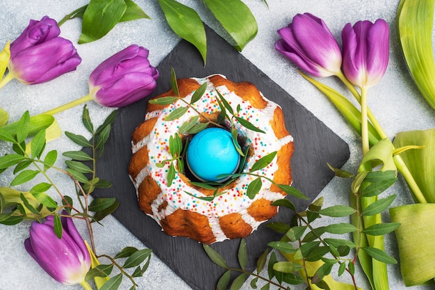 Osterkuchen in Puderzucker bemalte Eier und Tulpen auf dem Tisch. Draufsicht hautnah.