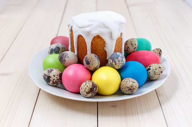 Osterkuchen und bunte Eier auf einer Platte auf einem Holztisch. Frohe Ostern-Konzept