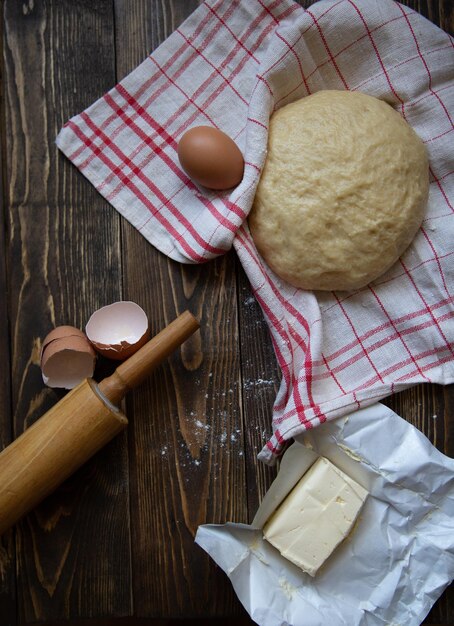 Osterkuchenzutaten Hefeteigrolling Pinkitchen TowelButter und Eierschale auf dunklem Hintergrund