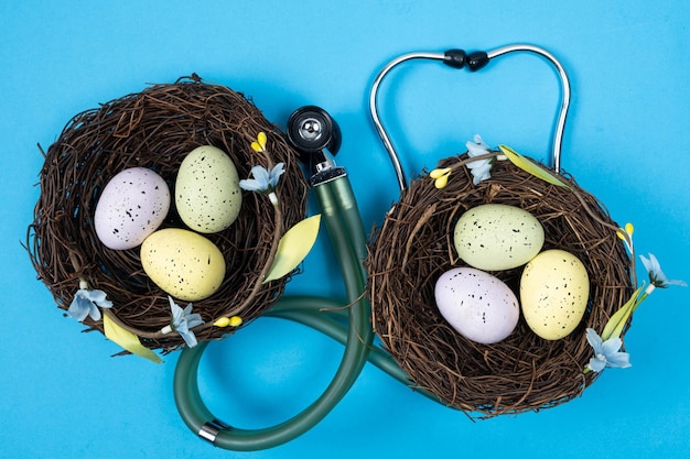 Ostermedizin Zwei Nester mit bemalten Eiern und einem Stethoskop auf blauem Hintergrund