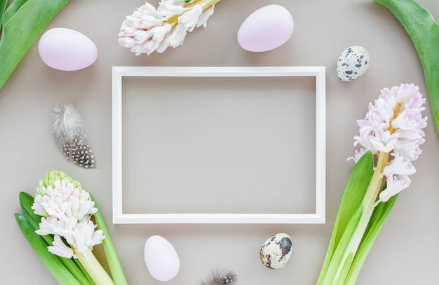 Ostermodell mit Ostereiern und Blumen mit weißem Rahmen auf neutralem Hintergrund