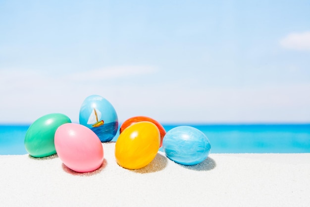 Ostern am tropischen Strand Hintergrund Eier auf dem weißen Sand Urlaubs- und Reisekonzept im Frühjahr