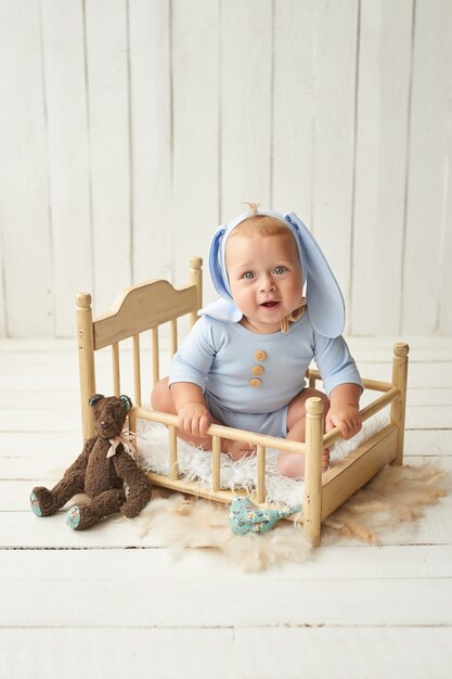 Ostern Baby sitzt auf Krippe. Osterhase. Glückliches Baby