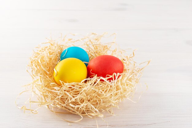 Ostern bemalte Eier in einem Nest auf einem hölzernen Hintergrund