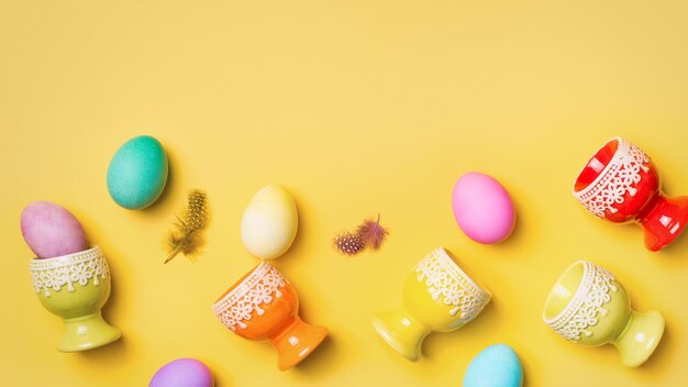 Ostern bunte flache Lage mit Eiern und dem Eierständerrahmen auf Draufsicht des gelben Hintergrundkopienraums