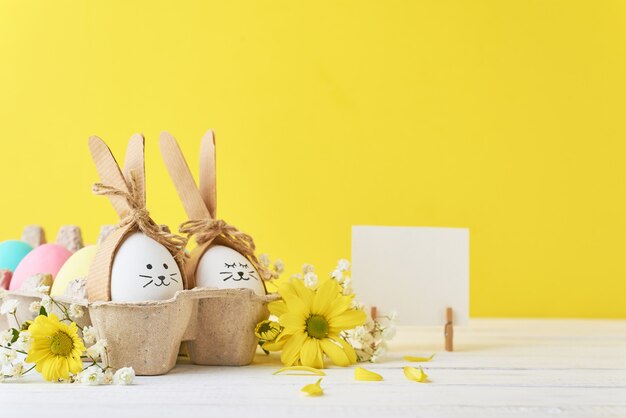 Ostern färbte Eier im Papierbehälter mit decorationd auf einem gelben Hintergrund