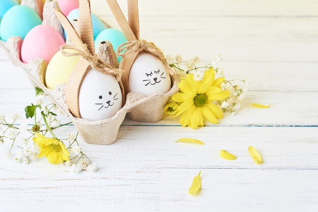 Ostern färbte Eier mit gemalten Gesichtern im Papierbehälter mit decorationd auf einem weißen Hintergrund