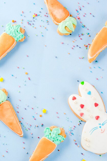 Ostern-Feiertagskonzept, süße Plätzchen in der Form von Karotten, Osterhase, mit Bonbon besprüht, hellblaue Draufsicht des Hintergrundkopienraumes, Grußkartenhintergrund