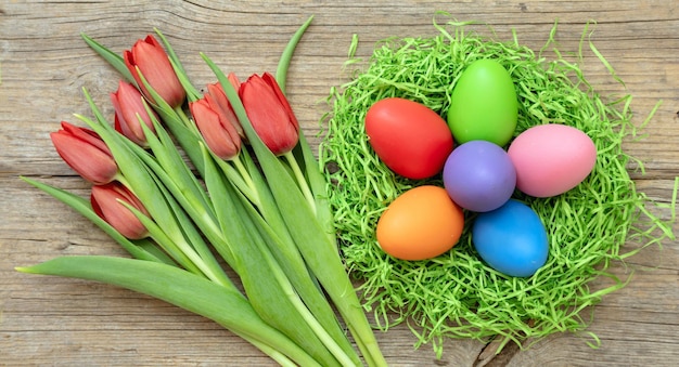 Ostern Frühlingsferien Frisches Tulpen- und Pastellfarben-Ei-Nest auf Holztisch oben