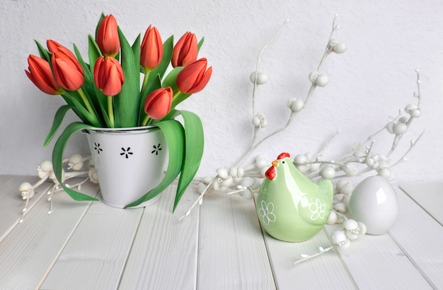 Ostern-Grußkartendesign mit Bündel roten Tulpen, keramischer Henne und Ei auf Weiß