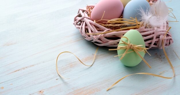 Ostern-Hintergrund mit Ostereiern im Nest auf dem blauen hölzernen Hintergrund mit Kopienraum.