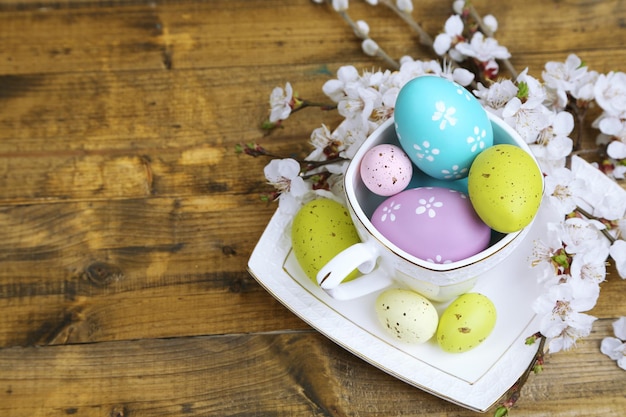 Ostern-Komposition mit blühenden Zweigen auf Holztisch in der Nähe