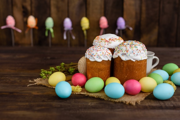 Ostern-Kuchen und bunte Eier auf einem Holztisch.