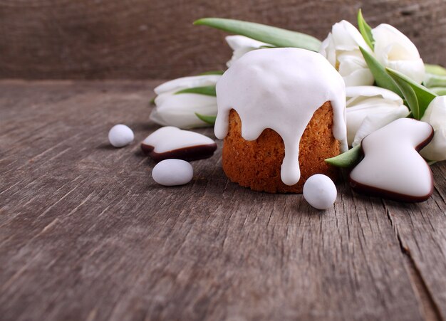 Ostern-Kuchen, weiße Tulpen, Schokoladenhase und Eier auf einem hölzernen Hintergrund. Platz kopieren.