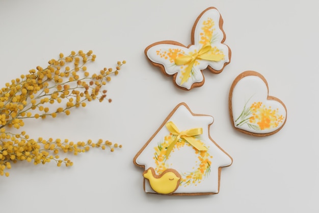 Ostern Lebkuchenplätzchen und Mimosenblumen auf weißem Hintergrund. Kopierbereich der Draufsicht. Frohe Ostern Konzept.