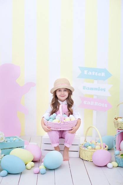 Ostern! Mädchen hält einen Korb mit bunten Ostereiern. Bunte Wohnkultur Ostern. Mädchen, das Ostereier jagt. Frühlingsdekoration, Familienfeier. Kleiner Bauer. Ernte. Bauernhof. Feder Interieur