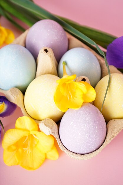 Ostern malte Eier in Eierablage mit Blumen auf gelbem Hintergrund. Nahansicht