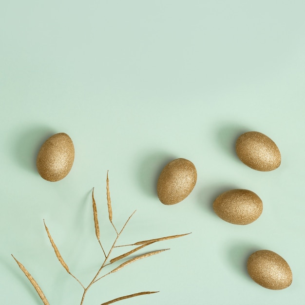 Ostern mit hellen Eiern, glänzenden goldfarbenen Eiern und Zierkräutern