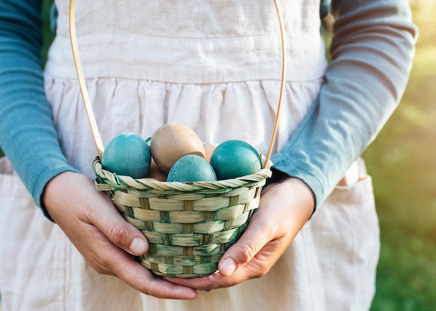 Ostern rustikal gefärbte Eier im Weidenkorb in den Händen einer Frau im Leinentuch Urlaub Konzept