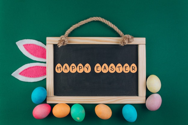 Ostern-Zusammensetzung mit Tafel, farbigen Eiern und den Hasenohren