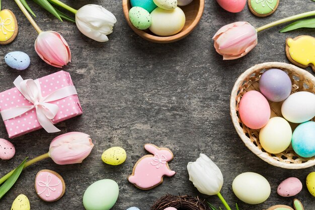 Osterrahmen mit Eiern Geschenkeschachtel und Tulpe auf einem farbigen Hintergrund Das minimale Konzept Top View Glückliche Osterkomposition Karte mit einem Kopierraum der Stelle für den Text