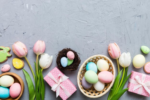 Osterrahmen mit Eiern Geschenkeschachtel und Tulpe auf einem farbigen Hintergrund Das minimale Konzept Top View Glückliche Osterkomposition Karte mit einem Kopierraum der Stelle für den Text