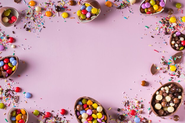 Osterrahmen mit Schokoladeneiern und Süßigkeiten auf rosa Hintergrund. Kopieren Sie Platz, Draufsicht, flache Lage