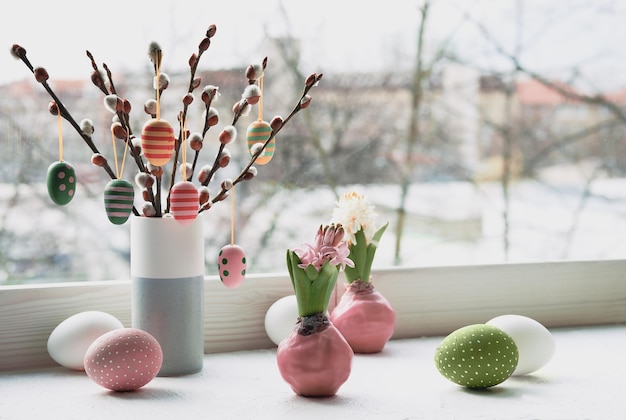 Osterschmuck auf Fensterbank, Panoramabild. Hölzerne bemalte Eier auf Weidenkätzchen. Hyazinthenblüten mit Zwiebeln in rosa Wachs. Fenster, Blick über die Stadt. Romantische Inneneinrichtung. Frohe Ostern