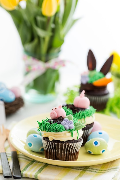Osterschokoladen-Cupcakes verziert mit Schweinchen und Hasenohren.