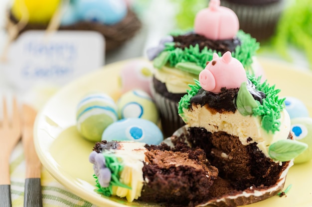 Osterschokoladen-Cupcakes verziert mit Schweinchen und Hasenohren.