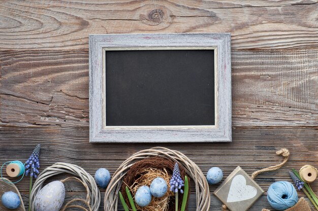 Ostertafel mit Ostereiern, Blumen und Frühlingsdekorationen auf Holz, Textraum