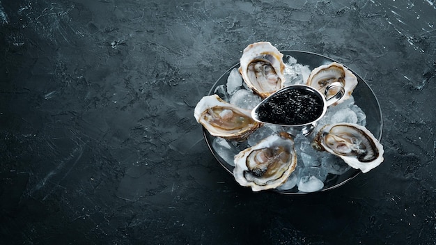 Ostras y caviar negro en un plato de hielo y limón Mariscos Vista superior Espacio de copia libre