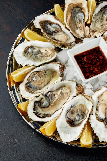 Ostras com limão servidas em travessa redonda preta Frutos do mar de luxo de delicatessen