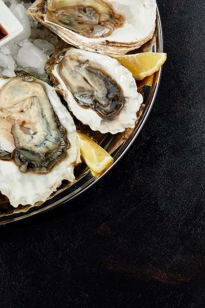 Ostras com limão servidas em travessa redonda preta frutos do mar de luxo de delicatessen