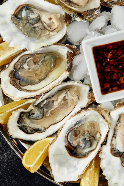 Ostras com limão servidas em travessa redonda preta Frutos do mar de luxo de delicatessen