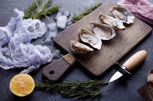 Foto ostras frescas abiertas, hielo y limón en un plato redondo, textura de piedra.