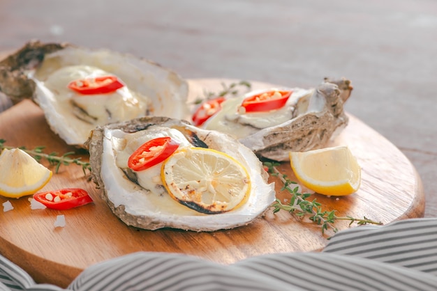 Ostras frescas con cáscara con limón sobre tabla de cortar