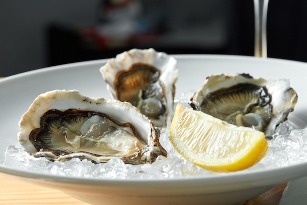 Ostras con limón en platos sobre una mesa con una copa de vino blanco