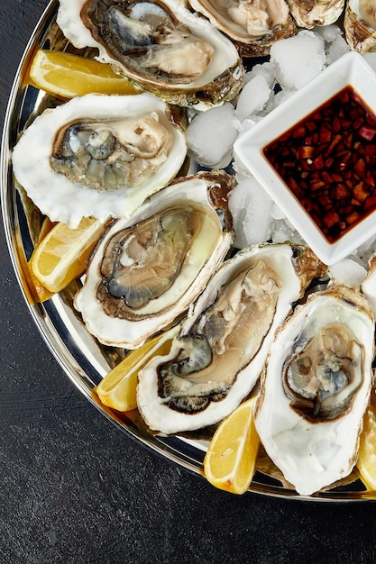 Ostras con limón servidas en un plato redondo negro Mariscos delicatessen de lujo