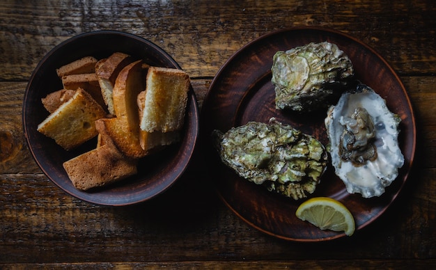 Ostras y pan tostado Moluscos de mar recién pescados Proteínas naturales con un trozo de limón