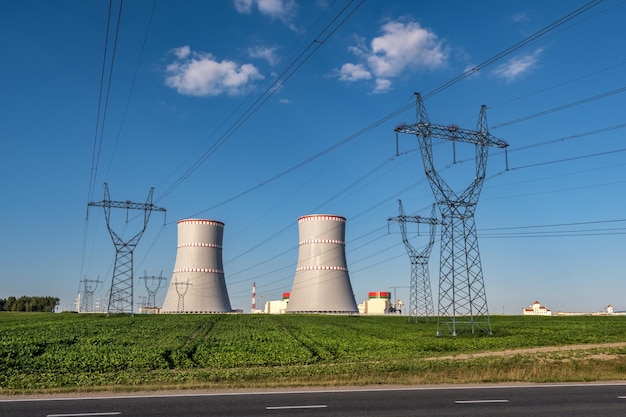 OSTROVEC WEISSRUSSLAND JULI 2020 Kühltürme des Kernkraftwerks mit Hochspannungsmasttürmen gegen den blauen Himmel