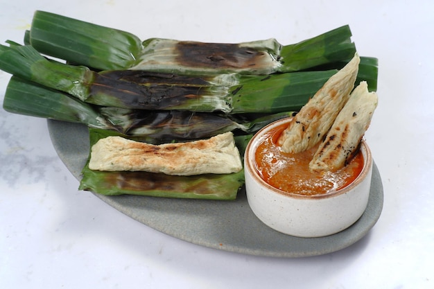 otak otak, bolinhos de peixe grelhado envoltos em folha de bananeira, servidos com molho picante