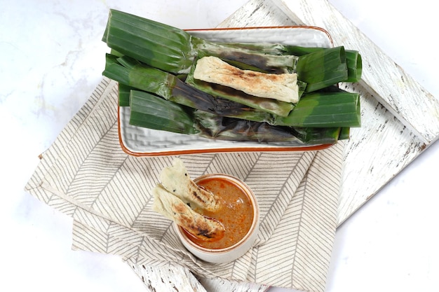 otak otak, bolinhos de peixe grelhado envoltos em folha de bananeira, servidos com molho picante